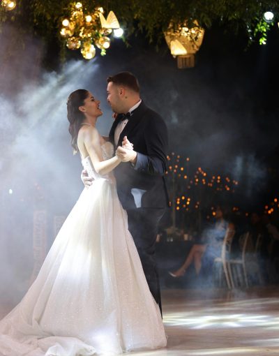 A beautifully dressed couple shares a romantic first dance at their wedding reception, surrounded by elegant decor.